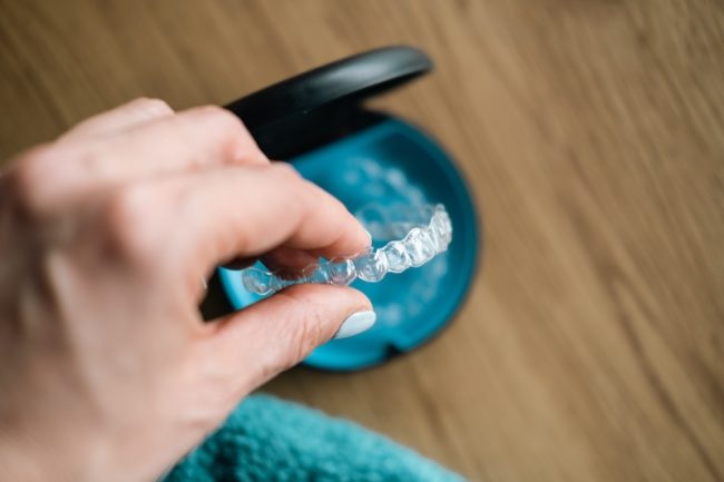 Woman’s hand holding  invisible aligners.